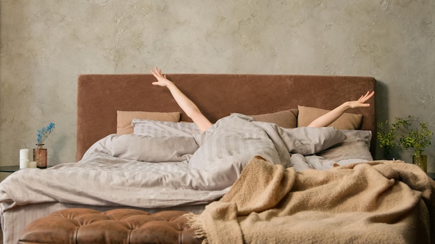 Mujer irreconocible soñolienta despertando acostada en una cómoda cama blanca chica desconocida estirando a mujer