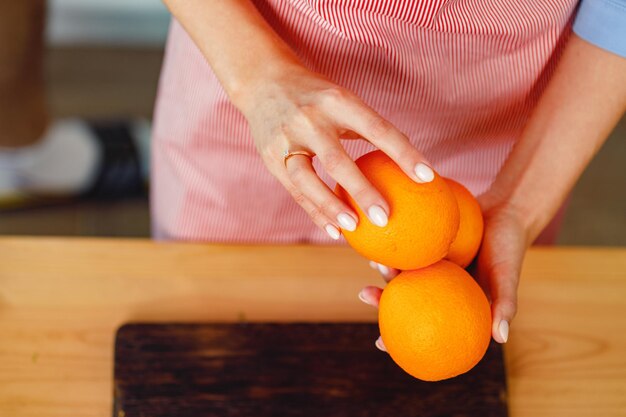 Mujer irreconocible sosteniendo naranjas mientras está de pie en la cocina