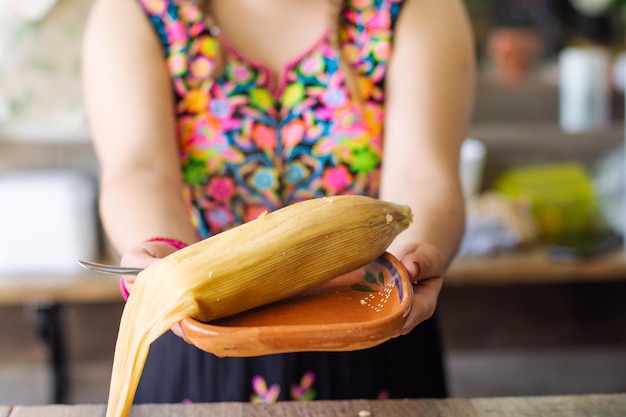 Mujer irreconocible con un tamal mexicano tradicional