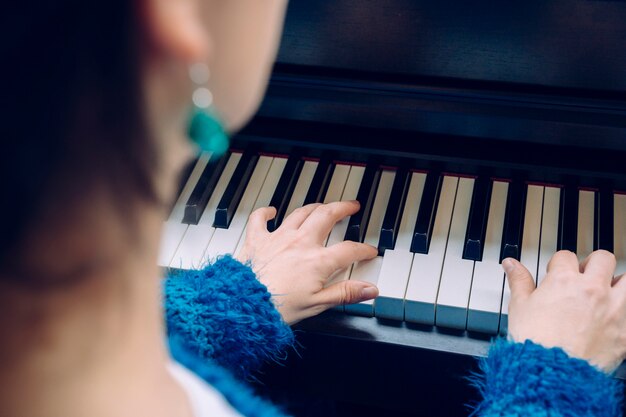 Mujer irreconocible tocando el piano. Detalle de las manos femeninas que tocan un teclado en casa. Profesor pianista músico ensayando música clásica. Músico profesional estilos de vida en interiores.