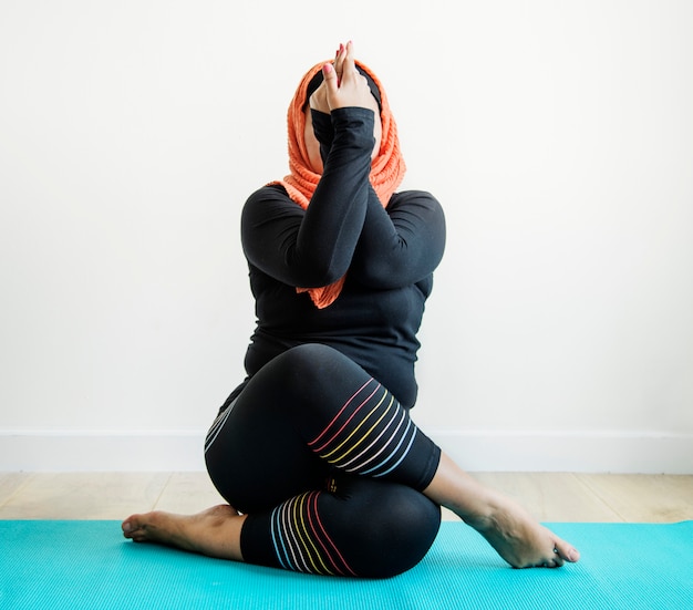 Mujer islámica haciendo yoga en la habitación.