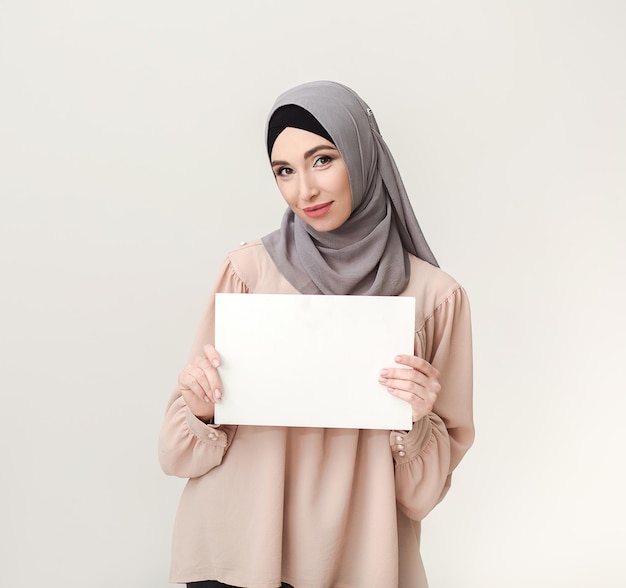 Mujer islámica con tablero en blanco sobre blanco