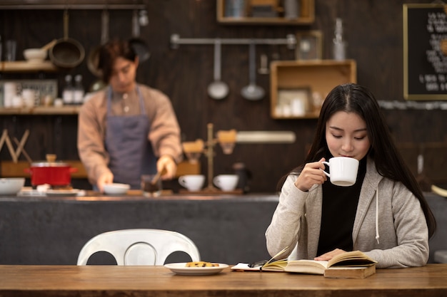 Foto mujer japonesa bebiendo café y leyendo un cuaderno en un restaurante