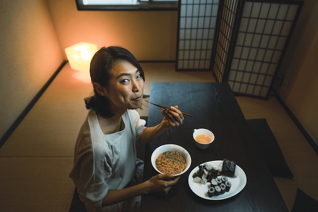 Mujer japonesa comiendo en un apartamento tradicional