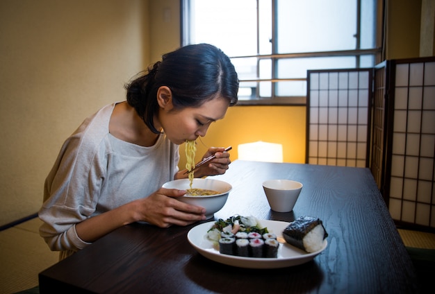 Mujer japonesa comiendo en un apartamento tradicional