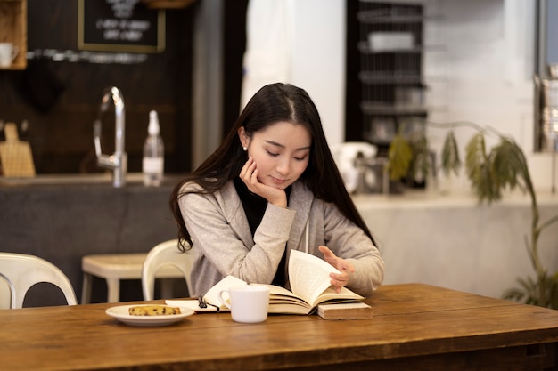 Mujer japonesa leyendo un cuaderno en un restaurante