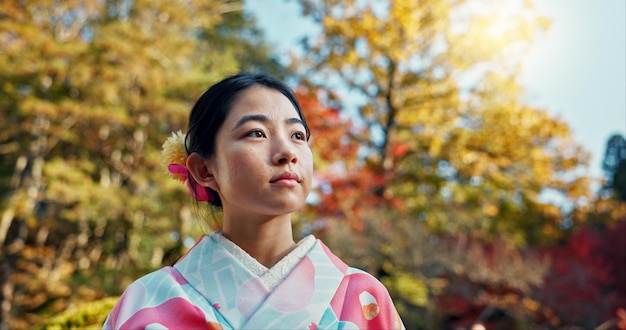 Foto mujer en el jardín asiática y tranquila con ventilador pensando en la vida con reflexión y tranquilidad en ropa tradicional paz parque japonés y naturaleza para el aire fresco con inspiración o visión