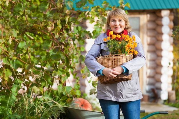 Una mujer en el jardín de otoño cosecha y elimina la basura.