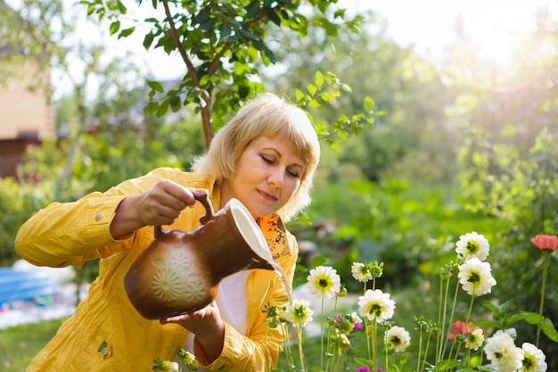 Una mujer en el jardín regando flores y plantas.