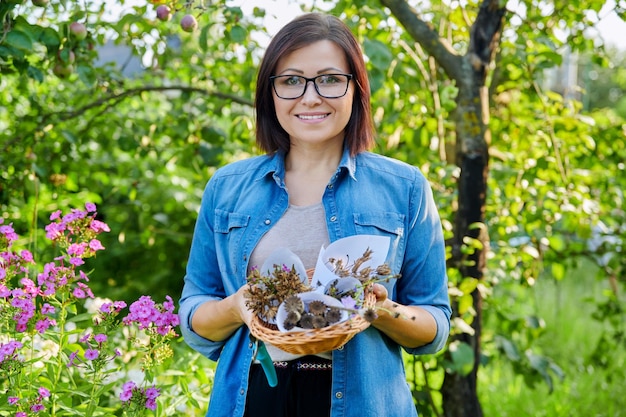 Mujer en el jardín de verano con semillas de plantas de flores secas recolectadas en la cesta