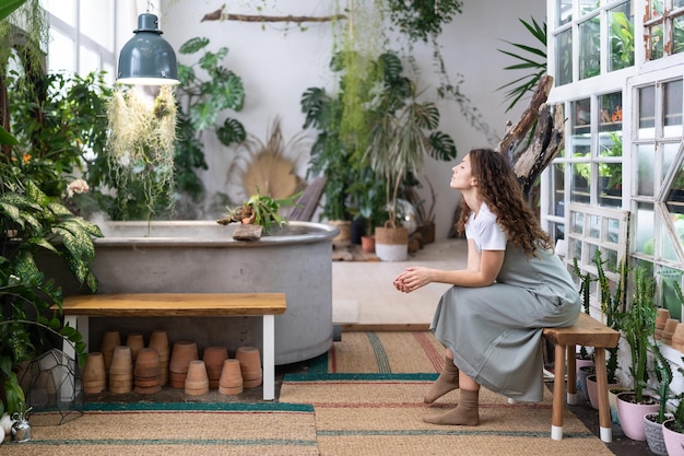 Mujer jardinera pensativa descansando después del trabajo en una tienda de flores o en un concepto de salud mental en invernadero