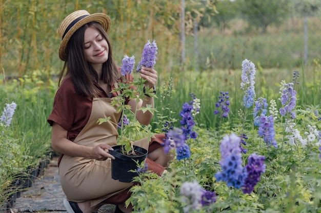 Mujer jardinero sostenga la planta verde en las manos en el patio trasero de la casa verde