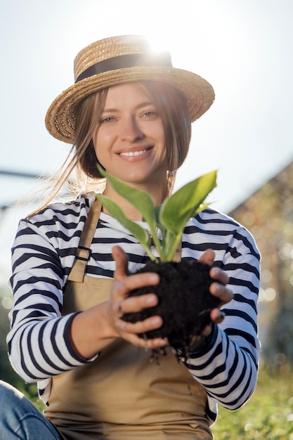 Mujer jardinero sosteniendo la planta en las manos en el jardín