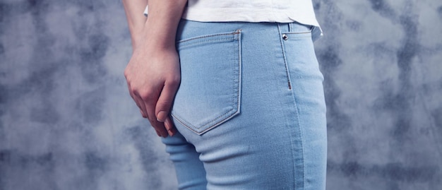 Mujer en jeans sostiene el culo. hemorroides