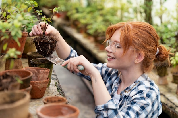Mujer de jengibre cuidando sus plantas en invernadero