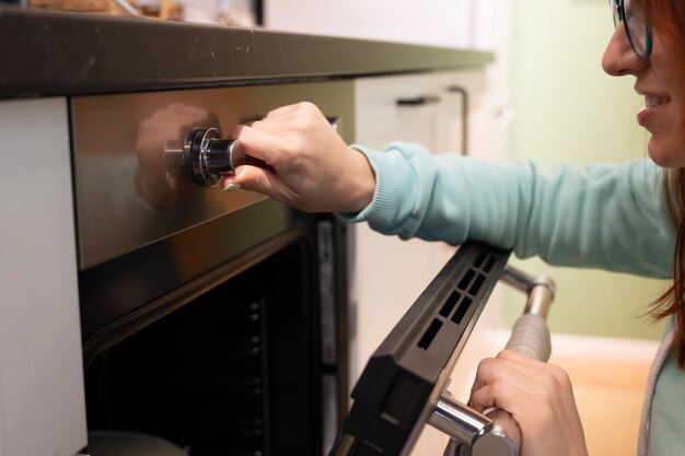 Una mujer joven abre el horno Ama de casa incluye un horno empotrado Niña cocina pasteles