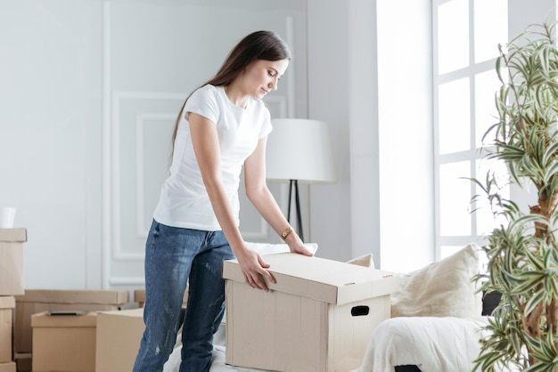 Mujer joven abriendo una caja en un apartamento nuevo