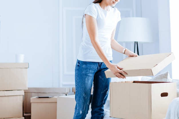 Mujer joven abriendo una caja en un nuevo apartamento mudarse a un nuevo apartamento