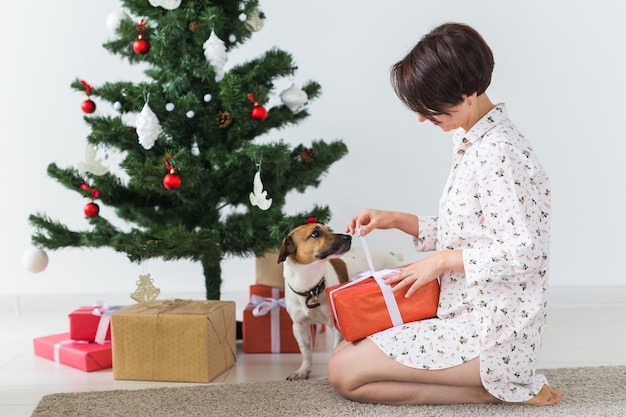 Mujer joven abriendo regalos de Navidad con su perro