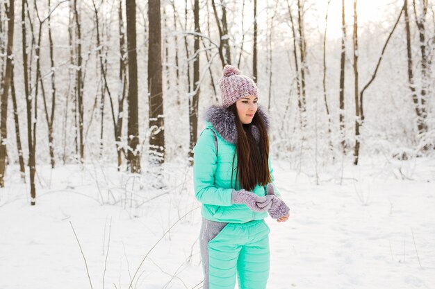 Mujer joven en abrigo de piel al aire libre en el jardín de nieve.
