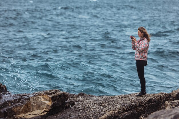 mujer joven, en, abrigo, en, playa, el mirar, asalto, mar