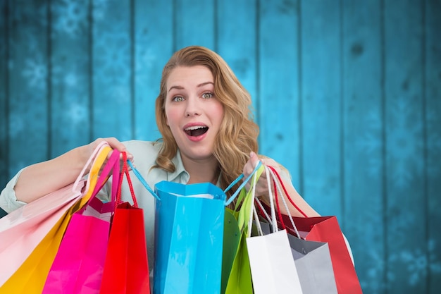 Mujer joven abrumada con bolsas de compras contra copos de nieve borrosos en tablones