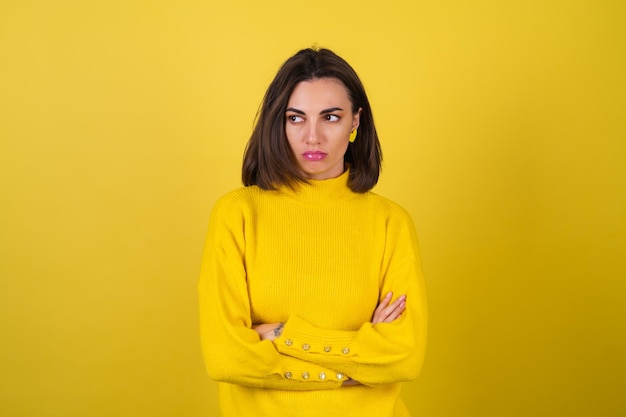 Mujer joven en un acogedor suéter amarillo con brillo de labios rosa brillante está molesta, ofendida, infeliz