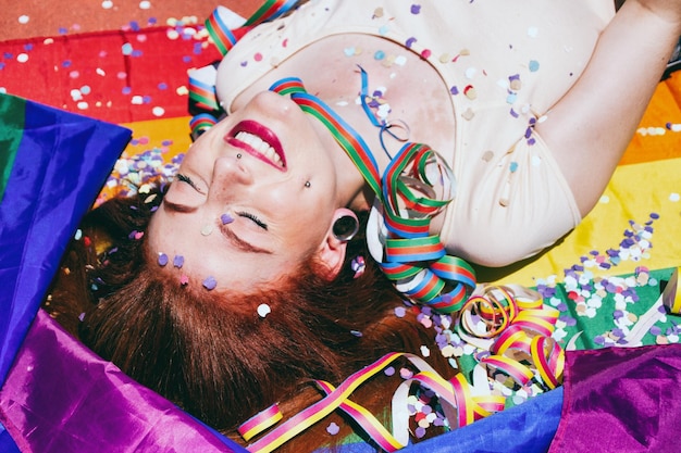 Mujer joven acostada en una bandera arco iris durante un día soleado