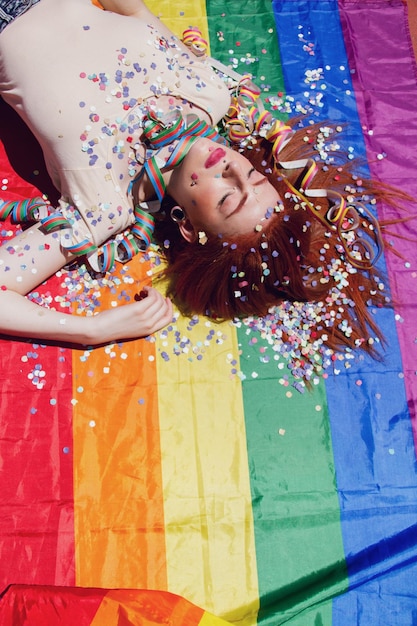 Foto mujer joven acostada en la bandera del arco iris