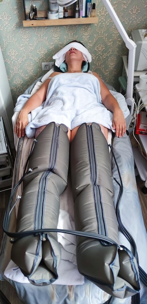 Mujer joven acostada en una camilla durante la sesión de terapia de presión en las piernas