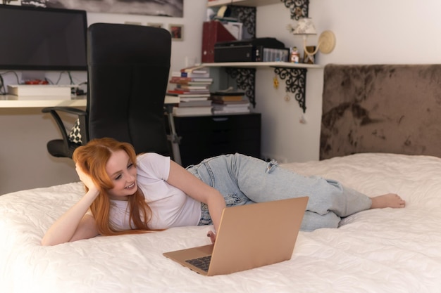 mujer joven, acostado, con, computador portatil, en cama, en casa