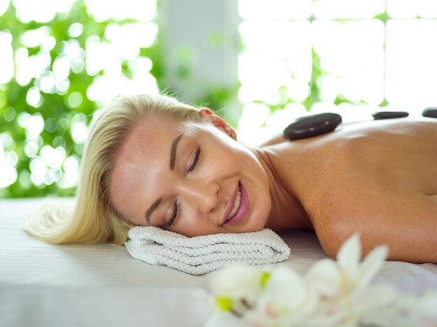 mujer joven, acostado, en, un, masaje, tablerelaxing, con, ojos cerrados, mujer, salón del balneario