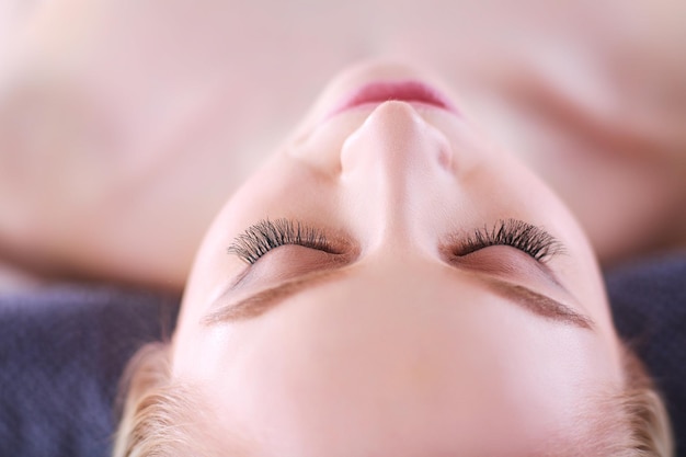 mujer joven, acostado, en, un, masaje, tablerelaxing, con, ojos cerrados