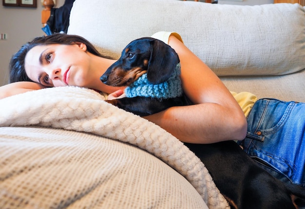 mujer joven, acostado, en, el, sofá, se abrazar, al lado de, ella, dachshund