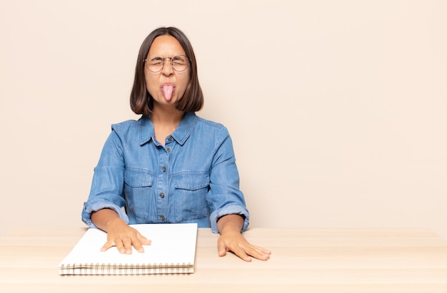 Mujer joven con actitud alegre, despreocupada, rebelde, bromeando y sacando la lengua, divirtiéndose