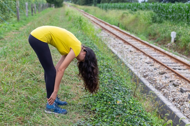 Mujer joven activa haciendo ejercicio de estiramiento en el campo