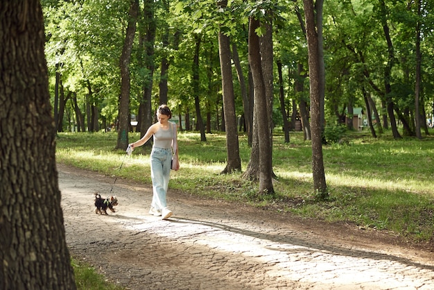 Mujer joven activa con un perro a pasear en una naturaleza de verano