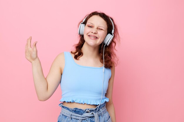 Mujer joven adolescente con auriculares música entretenimiento rosa fondo inalterado