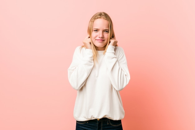 Mujer joven adolescente rubia cubriendo las orejas con las manos.