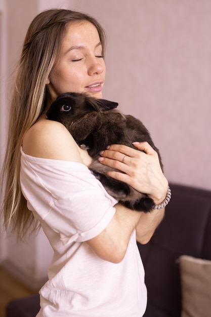 Mujer joven con adorable conejo en el interior de cerca adorable concepto de mascota y animal