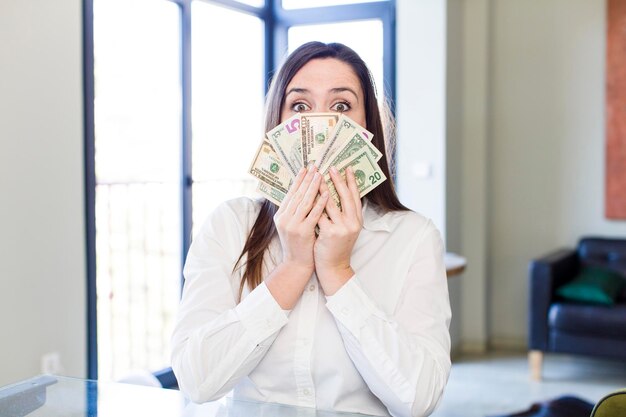 Mujer joven, adulta y bonita con billetes de un dólar en casa.