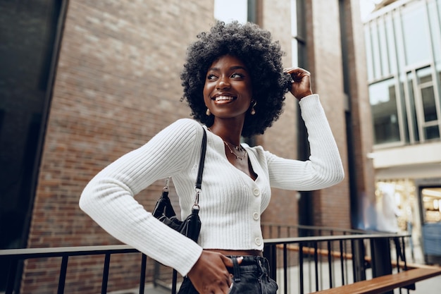 Mujer joven africana de pie en las calles de la ciudad al aire libre