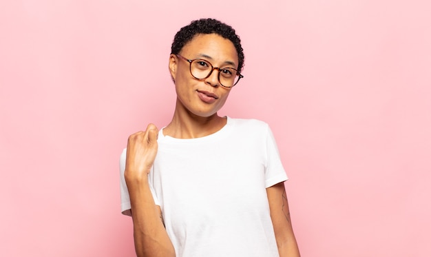 Mujer joven afro que parece arrogante, exitosa, positiva y orgullosa, apuntando a sí misma