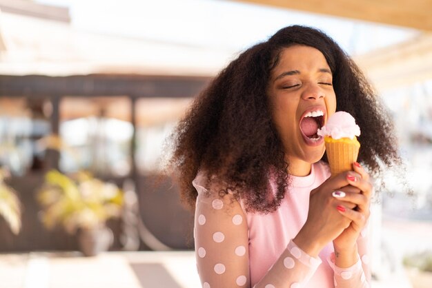 Mujer joven afroamericana con un helado de cornet al aire libre