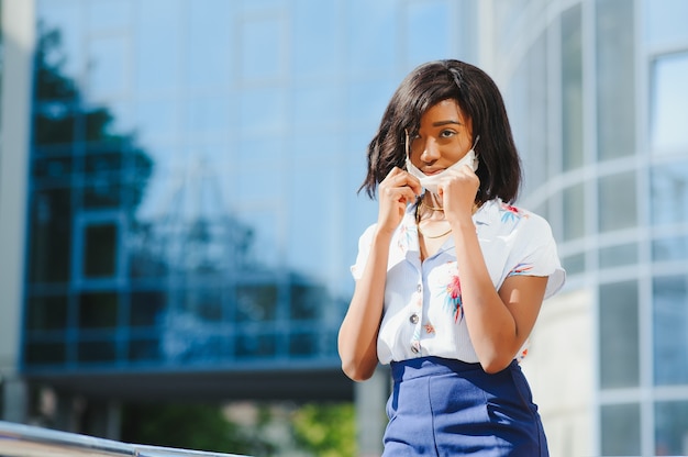 Mujer joven afroamericana con mascarilla al aire libre.