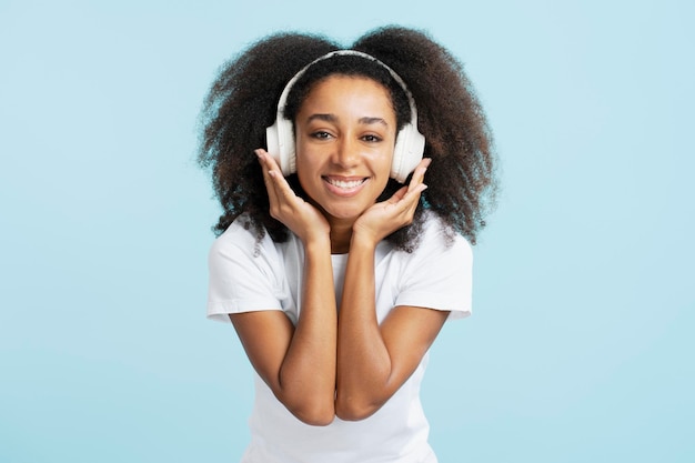 Mujer joven afroamericana con pelo rizado escuchando música divirtiéndose mirando la cámara