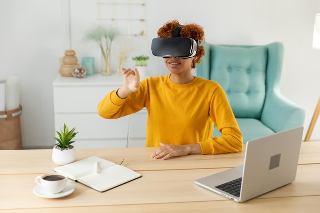 Mujer joven afroamericana usando realidad virtual metaverso VR gafas auriculares en casa Chica tocando aire durante la experiencia VR en casco de realidad virtual Simulación concepto de videojuego de alta tecnología