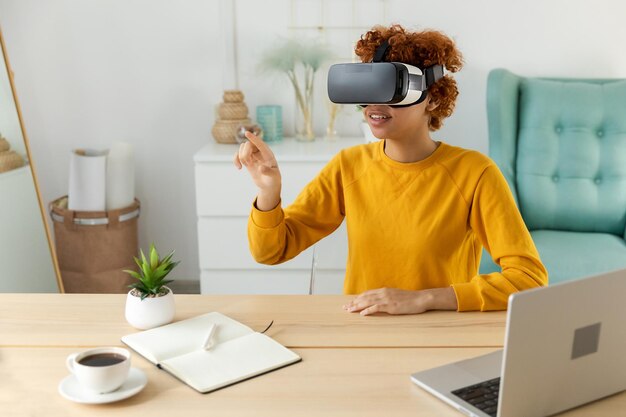 Mujer joven afroamericana usando realidad virtual metaverso VR gafas auriculares en casa Chica tocando aire durante la experiencia VR en casco de realidad virtual Simulación concepto de videojuego de alta tecnología