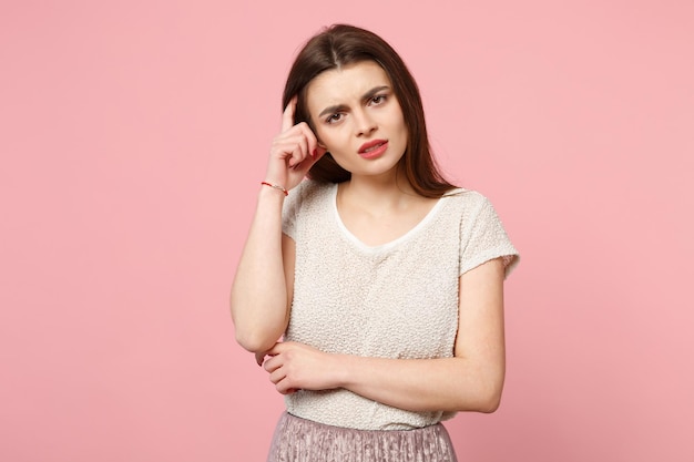 Mujer joven agotada con ropa ligera informal posando aislada en un fondo de pared rosa pastel, retrato de estudio. Gente emociones sinceras concepto de estilo de vida. Simulacros de espacio de copia. Ponerse la mano en la cabeza.