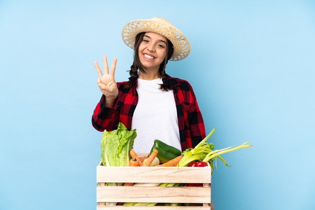 Mujer joven agricultor sosteniendo verduras frescas en una canasta de madera